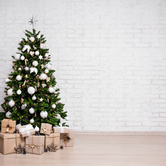 decorated christmas tree, heap of gift boxes over white brick wall with copy space