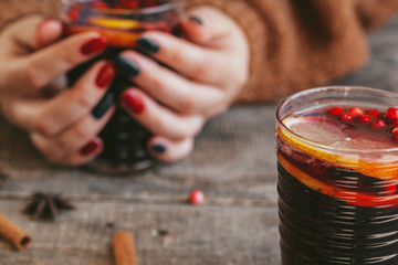 Woman's hands in warm sweater holding a cup of mulled wine