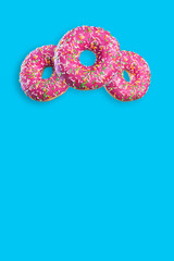  three pink donuts in the air on a color uniform background with a place for inscription