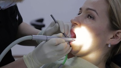 female dentist is treating a patient in dental clinic. Dental check up. Stomatologist treats caries in patient's teeth