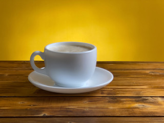 White coffee cup with cappuccino on wooden table