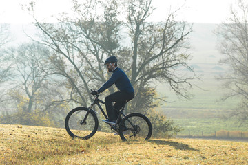 Fototapeta na wymiar Cyclist in pants and fleece jacket on a modern carbon hardtail bike with an air suspension fork rides off-road.