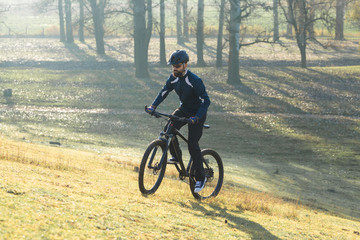 Fototapeta premium Cyclist in pants and fleece jacket on a modern carbon hardtail bike with an air suspension fork rides off-road.