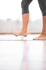 Close-up of legs of young girl with massage ball on wooden floor