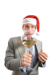 Businessman in Santa hat licking the rim of a huge wine glass with a surprised expression
