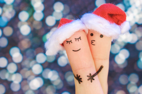 Fingers art of couple celebrates Christmas. Concept of man and woman hug in new year hats. Toned image.