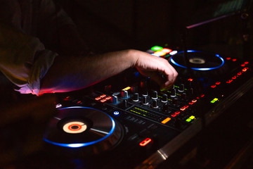 DJ desk in a nightclub party with hands. Studio DJ equipment glowing with light