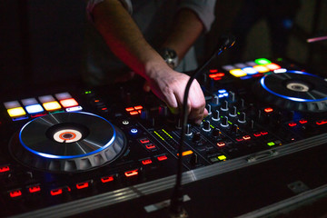 DJ desk in a nightclub party with hands. Studio DJ equipment glowing with light