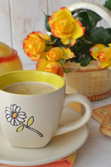 Hot latte coffee cup and beautiful yellow roses on shabby wooden background, vertical image