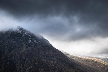 Obraz na płótnie Canvas Stunning detail landscape images of snowcapped Pen Yr Ole Wen mountain in Snowdonia during dramatic moody Winter storm