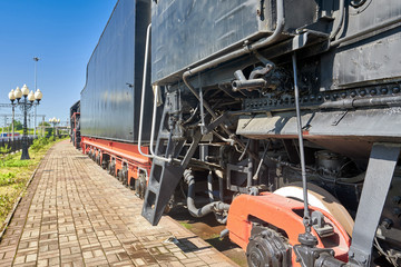 Fragment of an old steam train standing on rails at a railway station
