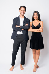 Full body shot of happy multi ethnic business couple smiling together with arms crossed