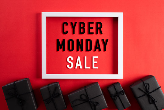Top view of Cyber Monday Sale text on white picture frame with black gift box and on red background. Shopping online concept and Cyber Monday composition.