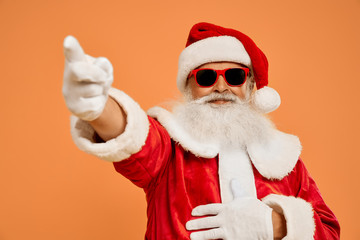 Senior bearded man in Santa costume pointing on by finger