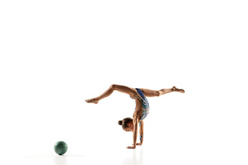 Obraz na płótnie Canvas Little flexible girl isolated on white studio background. Little female model as a rhythmic gymnastics artist in bright leotard. Grace in motion, action and sport. Doing exercises with the ball.