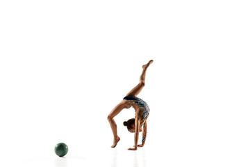 Little flexible girl isolated on white studio background. Little female model as a rhythmic gymnastics artist in bright leotard. Grace in motion, action and sport. Doing exercises with the ball.