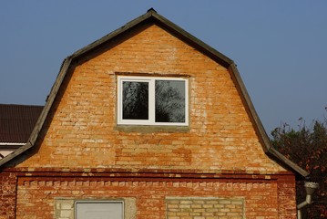 old brown loft brick house with one window on sky background