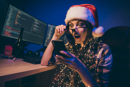 Photo of sad programmer workaholic lady work night meet newyear alone office hold telephone texting colleagues read good project news wear santa claus cap glasses indoors