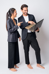 Full body shot of happy multi ethnic business couple working with laptop together