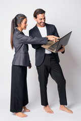 Full body shot of happy multi ethnic business couple working with laptop together