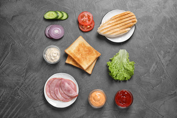Fresh ingredients for tasty sandwich on grey background, flat lay