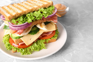 Tasty sandwich with chicken, ham and bacon on grey table, closeup