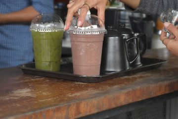 Staff prepare to serve cold drinks in plastic glasses.