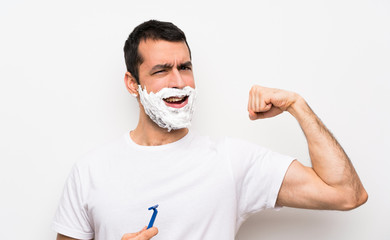 Man shaving his beard over isolated white background doing strong gesture
