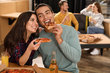 Young couple eating delicious pizza in cafe