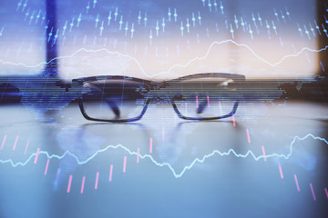 Financial graph hologram with glasses on the table background. Concept of business. Double exposure.