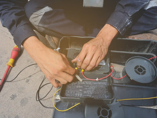 Selective focus of the technician is checking the condition of the battery by battery tester. 