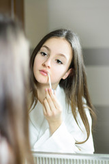 Female beauty, beautiful teen girl applying make up in bathroom at home.