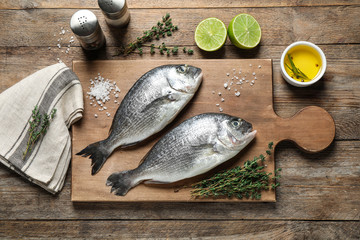 Flat lay composition with raw dorada fish on wooden table