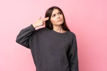 Fototapeta premium Young woman over isolated pink background with problems making suicide gesture