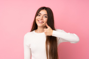 Young woman over isolated pink background giving a thumbs up gesture