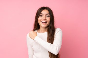 Young woman over isolated pink background celebrating a victory