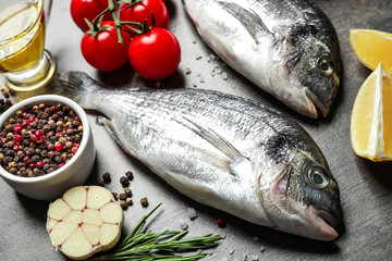 Raw dorada fish on grey table, closeup