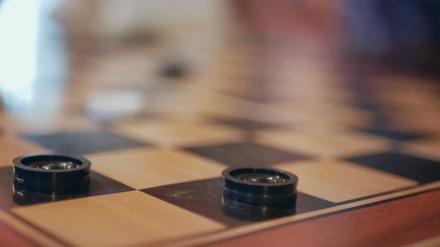 A game of checkers. a white figure captures dark figures. close-up