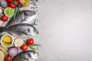 Flat lay composition with dorada fish on light grey table, space for text