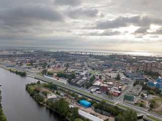 Fototapeta na wymiar Drone view of the industrial part of St. Petersburg, Kanonersky island with Western high-speed diameter and the Gulf of Finland on the horizon