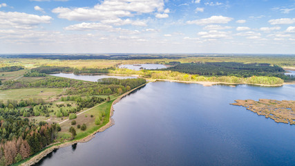 Fototapeta na wymiar Jezioro z lotu ptaka. Krajobraz z wodą, lasem i niebem. Spokojny letni dzień nad jeziorem.