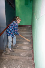 cleaning lady sweeping trash on the steps of the house near the elevator shaft