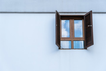 Window with wooden shutters on white stucco wall and copy space