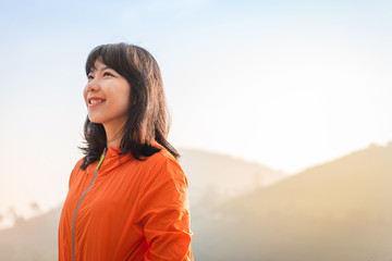 Portrait of Asian woman in orange jacket is smiling.