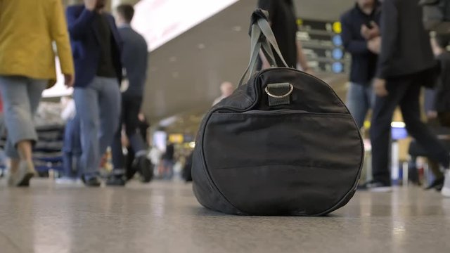 bag of explosives left by terrorist at the airport. Blurred background. sports bag on floor at the airport on the background of walking crowd of passengers.