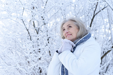 Fototapeta na wymiar Portrait of happy beautiful senior woman posing in snowy winter park