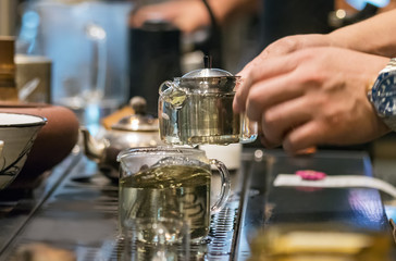 Barista male hands holding a glass teapot with tea in strands at a coffe shop counter in Busan, South Korea.