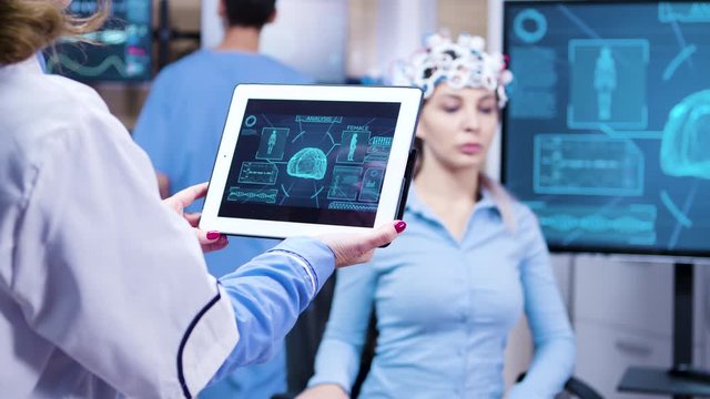 Middle age female doctor holding tablet with patient brain activity