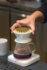 Barista male hand checking a dripper while making filter coffee.