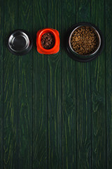 top view of bowls with pet food in row on green wooden surface with copy space